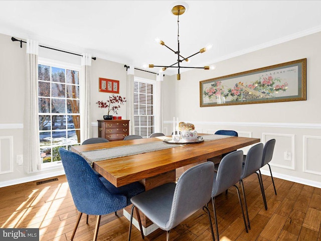 dining area featuring hardwood / wood-style flooring, ornamental molding, and an inviting chandelier