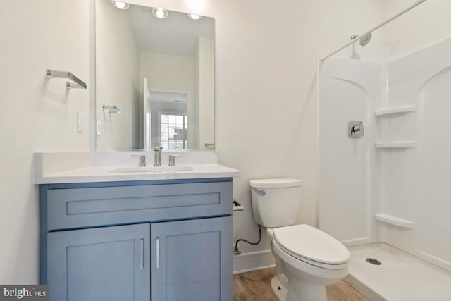 bathroom with hardwood / wood-style flooring, vanity, a shower, and toilet