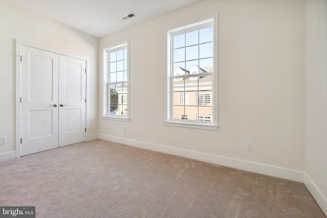 unfurnished bedroom featuring light carpet and a closet