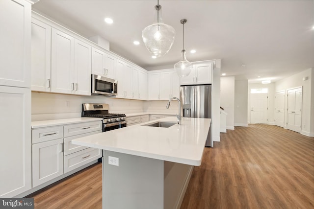 kitchen featuring stainless steel appliances, white cabinetry, sink, and decorative light fixtures