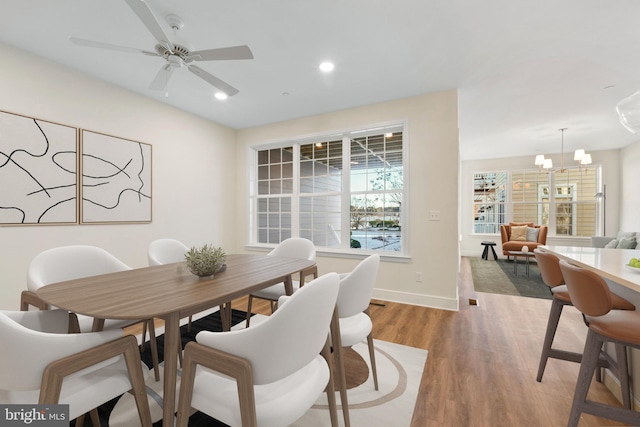 dining area featuring hardwood / wood-style floors and ceiling fan with notable chandelier