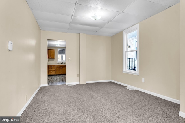 carpeted spare room featuring a drop ceiling and sink