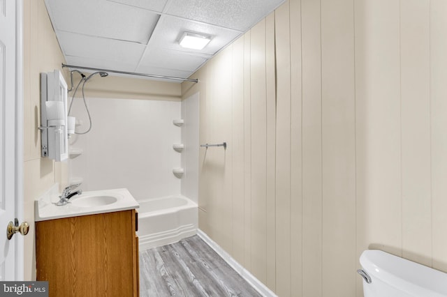 full bathroom with toilet, vanity, shower / bathing tub combination, wood-type flooring, and a paneled ceiling