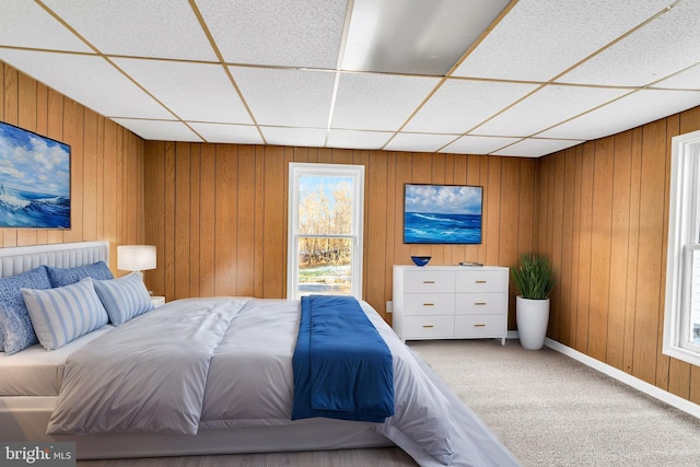 unfurnished bedroom featuring a paneled ceiling, wooden walls, and carpet flooring