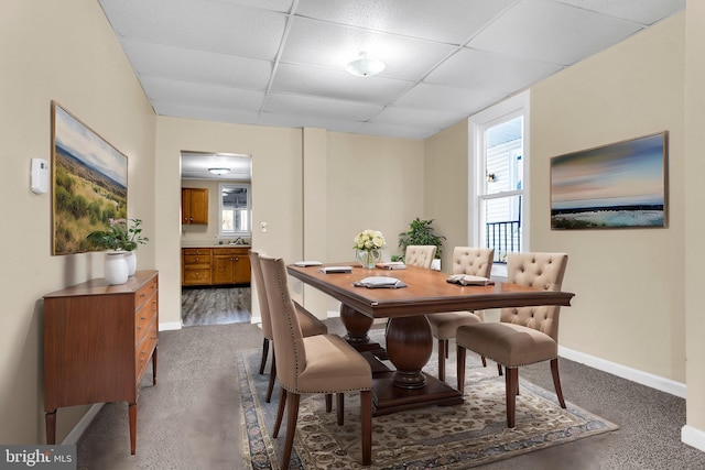 carpeted dining space with a drop ceiling and sink