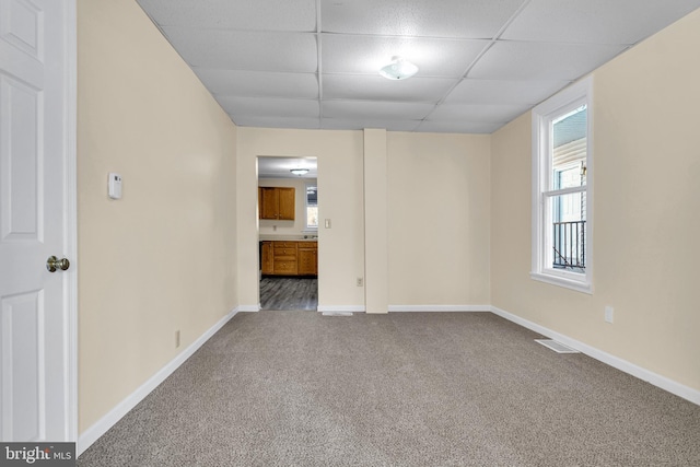 unfurnished room with a drop ceiling and carpet flooring