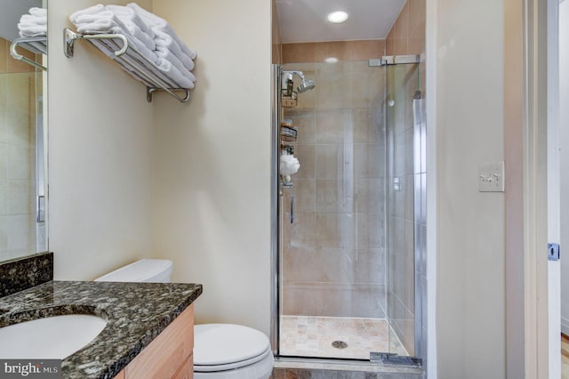 bathroom with vanity, toilet, and a shower with door