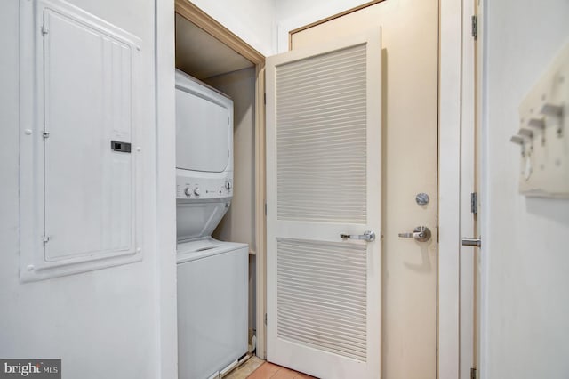 clothes washing area with stacked washer and dryer and electric panel