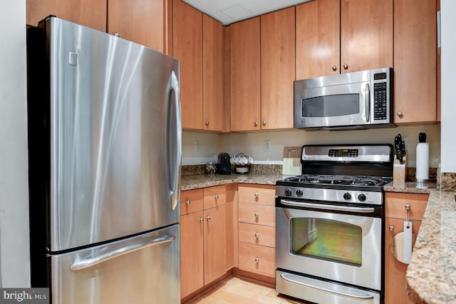 kitchen featuring appliances with stainless steel finishes and light stone counters