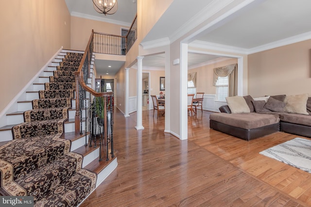 interior space featuring a notable chandelier, crown molding, wood-type flooring, and decorative columns