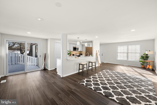 unfurnished living room featuring dark wood-type flooring and sink