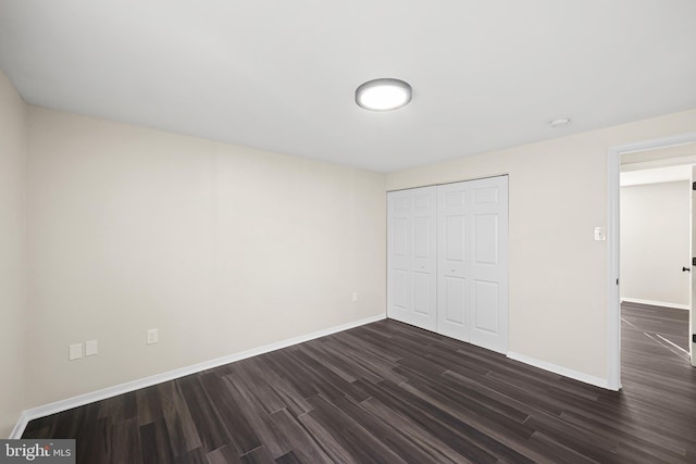 unfurnished bedroom with dark hardwood / wood-style floors and a closet