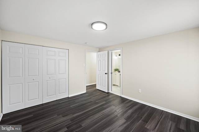 unfurnished bedroom featuring a closet, connected bathroom, and dark wood-type flooring