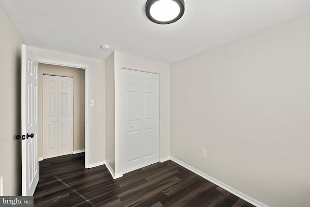 unfurnished bedroom with dark hardwood / wood-style floors and a closet