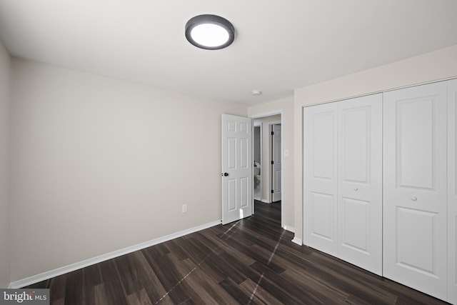 unfurnished bedroom with a closet and dark wood-type flooring