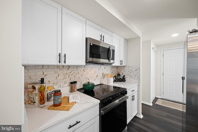 kitchen with backsplash, white cabinetry, appliances with stainless steel finishes, and dark hardwood / wood-style flooring