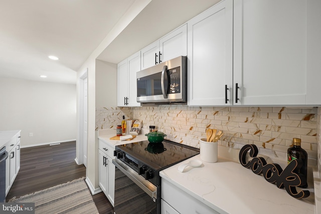 kitchen featuring tasteful backsplash, white cabinetry, dark wood-type flooring, and appliances with stainless steel finishes