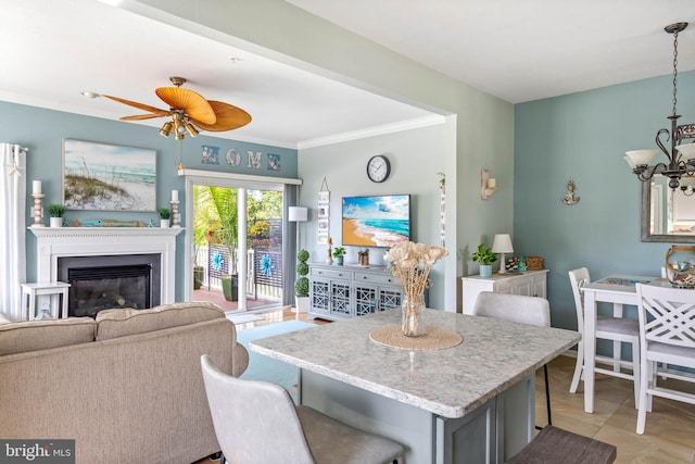 kitchen featuring light tile patterned floors, crown molding, ceiling fan with notable chandelier, and a kitchen breakfast bar