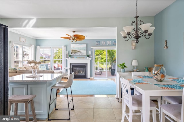 tiled dining room with ornamental molding and ceiling fan with notable chandelier