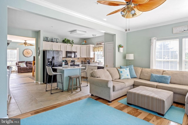 living room with crown molding, light hardwood / wood-style floors, and ceiling fan