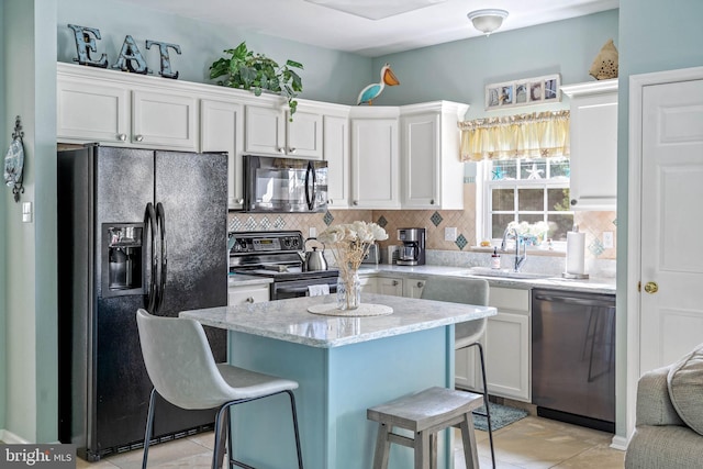 kitchen with a breakfast bar, sink, white cabinets, and black appliances