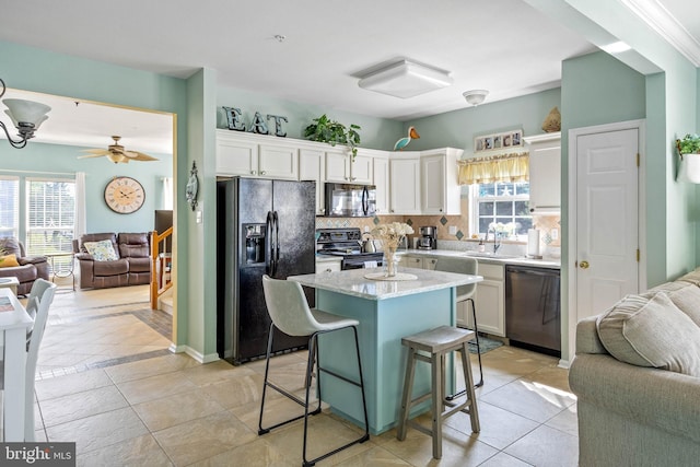 kitchen featuring white cabinetry, sink, a kitchen bar, light tile patterned floors, and black appliances