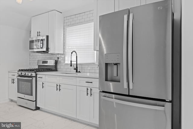 kitchen featuring white cabinets, appliances with stainless steel finishes, sink, and tasteful backsplash