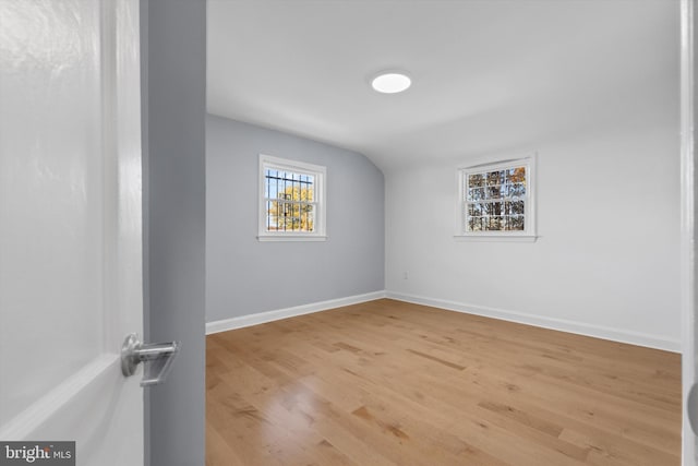 unfurnished room with hardwood / wood-style flooring and vaulted ceiling