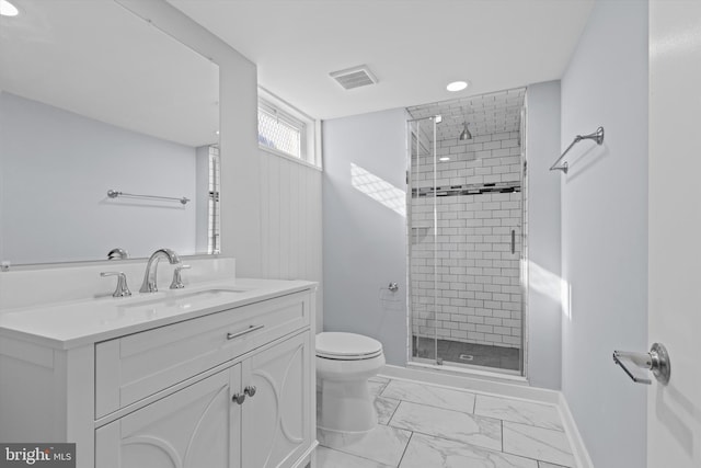 bathroom featuring toilet, vanity, and a shower with door