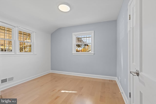 empty room featuring lofted ceiling and light hardwood / wood-style flooring