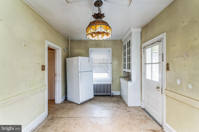 kitchen with hanging light fixtures, radiator, white refrigerator, and white cabinetry