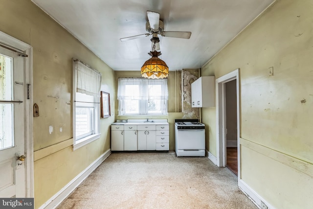 kitchen with ceiling fan, white cabinets, white range, and sink