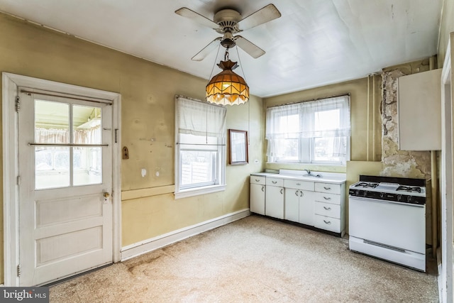 kitchen featuring ceiling fan, white cabinets, white range with gas cooktop, and a healthy amount of sunlight