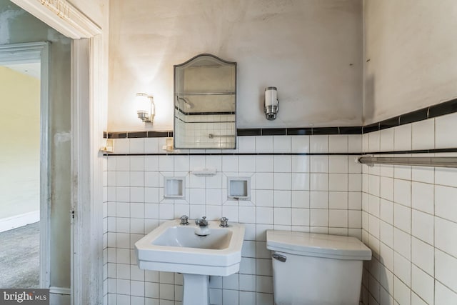 bathroom featuring sink, tile walls, and toilet