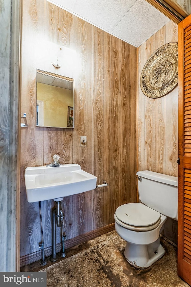 bathroom with sink, a textured ceiling, toilet, and wooden walls