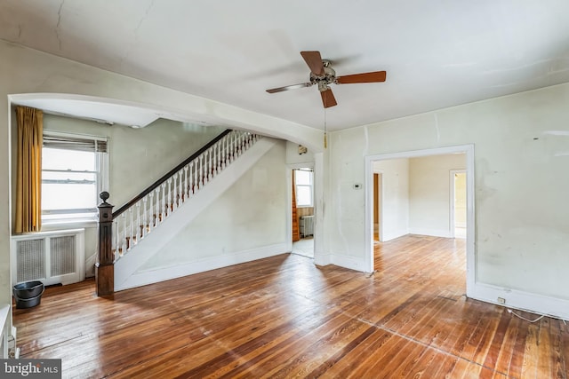 unfurnished living room with ceiling fan, wood-type flooring, and radiator heating unit