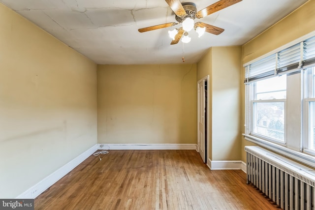 spare room featuring ceiling fan, radiator heating unit, and hardwood / wood-style flooring