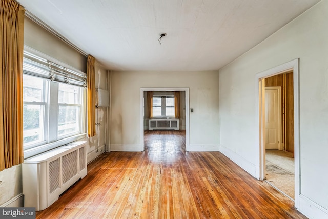 empty room featuring wood-type flooring and radiator heating unit