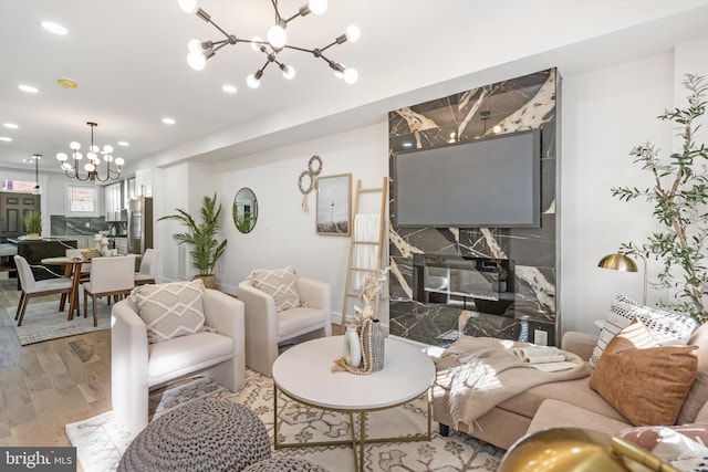 living room with wood-type flooring, a high end fireplace, and a chandelier