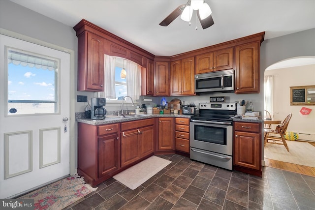 kitchen featuring ceiling fan, appliances with stainless steel finishes, sink, and dark stone counters