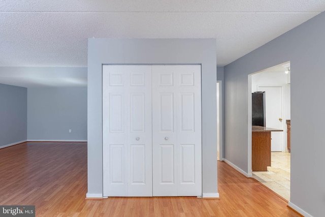 unfurnished bedroom with light hardwood / wood-style floors, a textured ceiling, and a closet