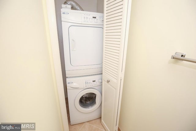 laundry room with stacked washer and clothes dryer and light tile patterned flooring