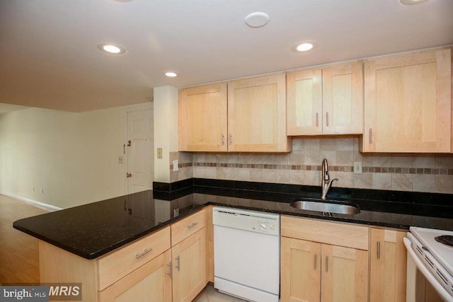 kitchen featuring kitchen peninsula, sink, white appliances, and dark stone countertops