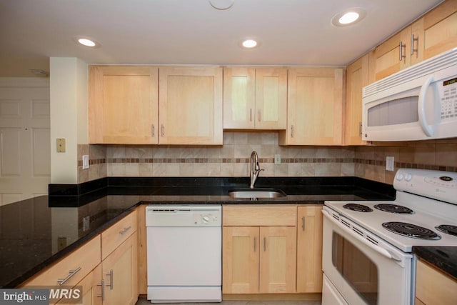 kitchen featuring decorative backsplash, light brown cabinets, white appliances, dark stone countertops, and sink