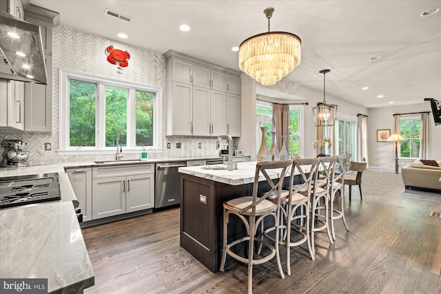 kitchen with dishwasher, a kitchen island, pendant lighting, light stone counters, and sink