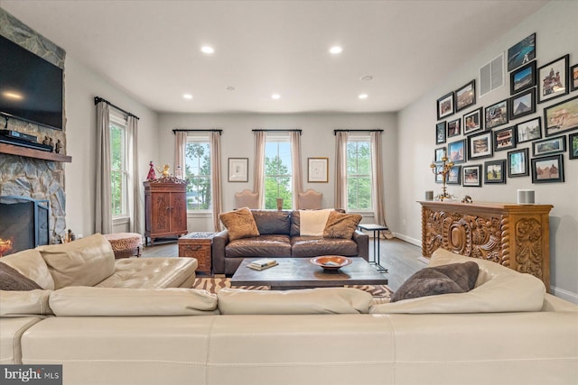 living room featuring a stone fireplace and hardwood / wood-style floors