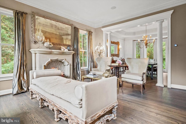 living area with hardwood / wood-style flooring, decorative columns, crown molding, and an inviting chandelier