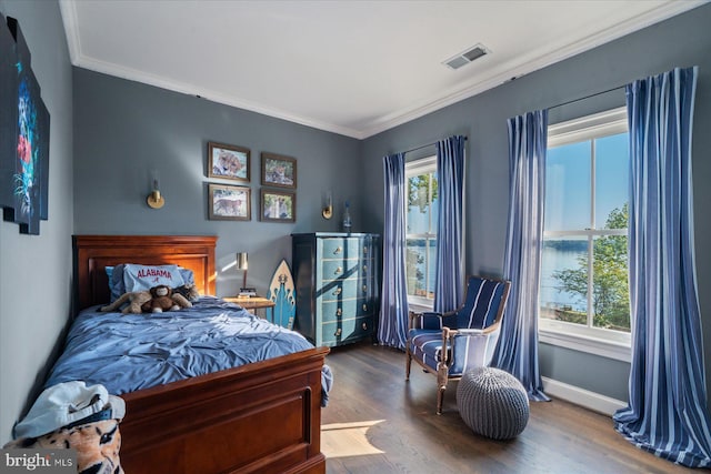 bedroom featuring crown molding, a water view, wood-type flooring, and multiple windows