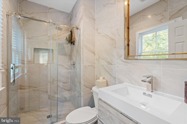 bathroom with tile walls, toilet, a shower with door, and vanity