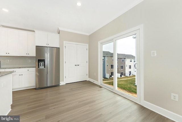 kitchen featuring white cabinetry, stainless steel fridge, backsplash, light stone countertops, and a wealth of natural light